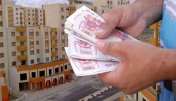 Personne comptant de l'argent devant des bâtiments en construction.