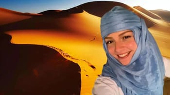 Femme souriante portant un hijab dans un désert doré.
