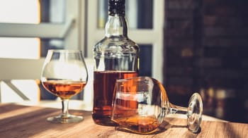 Verre d'alcool frelaté avec bouteille sur une table en bois.