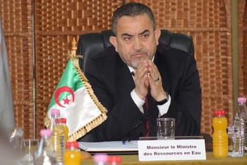 Arezki Berraki, ancien ministre, en réunion officielle avec drapeau algérien.