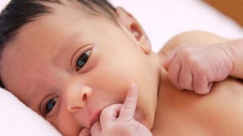 Bébé nouveau-né à Berlin avec doigt dans la bouche, sommeil paisible.
