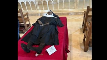 Corps d'une nonne allongée sur un lit avec vêtements religieux.