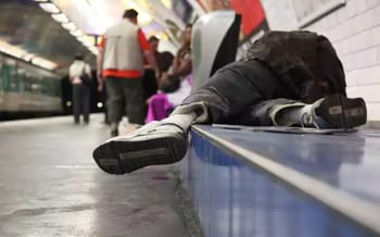 Homme sans-abri allongé sur le sol d'une station de métro.