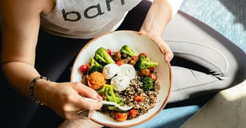 Personne mangeant une salade équilibrée avec légumes et quinoa.