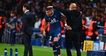 Kylian Mbappé blessé sur le terrain avec un entraîneur lui donnant des soins.