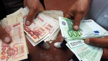 Personnes échangeant des billets de banque en euros et dinars.