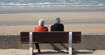 Deux personnes âgées assises sur un banc regardant la mer en Algérie.