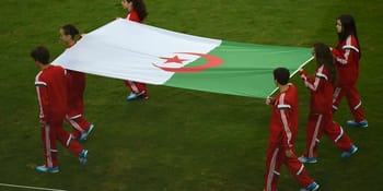 Jeunes sportifs algériens portant un drapeau national lors d'une cérémonie.