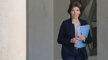 Femme politique souriante tenant des dossiers bleus.