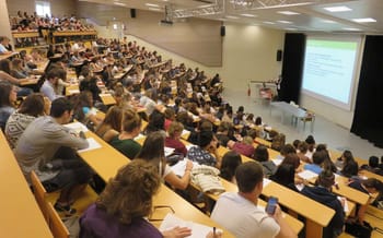 Étudiants attentifs lors d'une conférence dans un grand amphithéâtre.