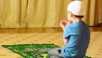 Jeune garçon en prière dans une salle d'école avec tapis de prière.