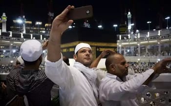 Homme prenant un selfie devant la Kaaba lors d'un pèlerinage.