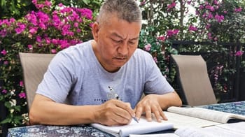 Homme concentré en train d'écrire lors d'un examen en plein air.