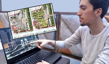 Jeune homme travaillant sur un plan architectural avec un ordinateur portable.