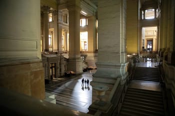 Vue intérieure d'un bâtiment historique avec colonnes et escaliers.
