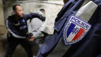 Agent de police municipale contrôlant un individu dans une rue.