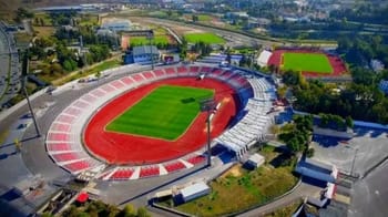 Stade de football avec piste d'athlétisme et tribunes modernes.