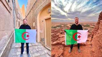 Touriste algérien tenant un drapeau en Maroc avec paysage désertique.