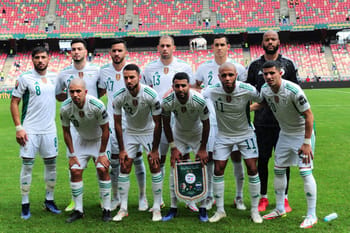 Groupe de joueurs algériens en tenue de football sur le terrain.
