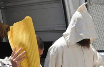 Imam marocain en prison, escorté par des agents de sécurité.