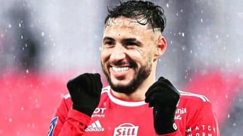 Youcef Belaïli souriant en tenue de football sous la pluie.
