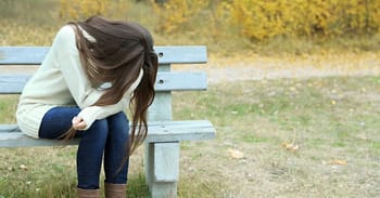 Jeune femme triste assise sur un banc dans un parc.