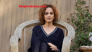 Femme avec cheveux bouclés assise dans un fauteuil en bois.