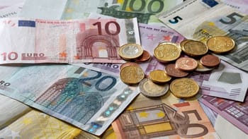 Billets et pièces en euros sur fond de billets en dinar algérien.