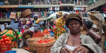 Femme dans un marché informel avec vendeurs et acheteurs.