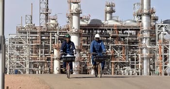 Deux travailleurs à vélo dans une usine pétrolière en Algérie.
