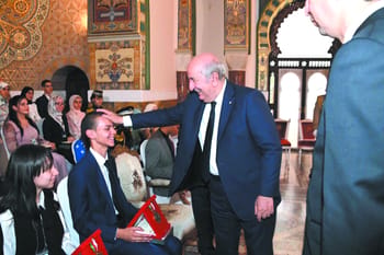 Président algérien félicite des étudiants lors d'une cérémonie officielle.
