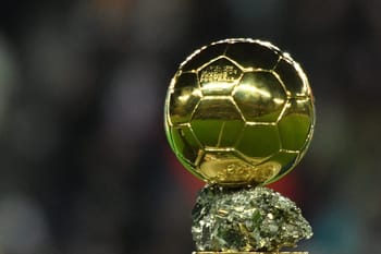 Ballon d'Or 2023 en or brillant sur un socle en pierre.