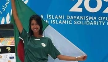 Athlète féminine en tenue verte avec drapeau lors des Jeux Arabes.