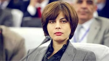 Houda Faraoun en réunion officielle, visage sérieux et concentré.