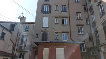 Façade d'un immeuble résidentiel avec fenêtres et balcons.