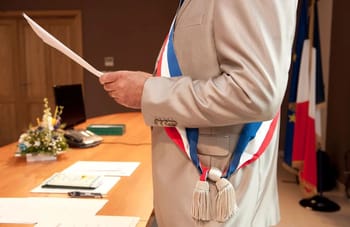 Homme en costume avec médaille lors d'une cérémonie officielle.