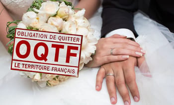 Mains de mariés avec bouquet et panneau OQTF en France.