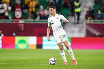 Joueur de football algérien portant le maillot numéro 20 sur le terrain.