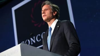 Homme en costume parlant lors d'une conférence internationale.
