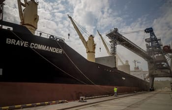 Navire militaire en dock avec grues industrielles en arrière-plan.