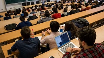 Étudiants en classe universitaire avec ordinateurs et notebooks.