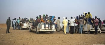 Migrants entassés dans des véhicules en déplacement dans un désert.