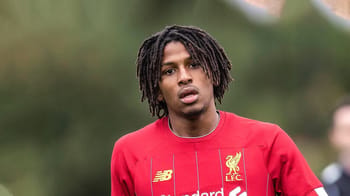 Yasser Larouci en maillot de football rouge, portrait en plein air.