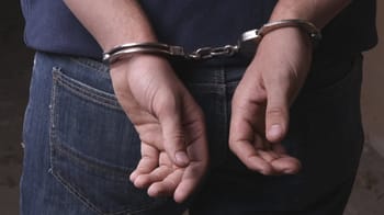 Suspect en garde à vue avec poignets liés par des menottes.