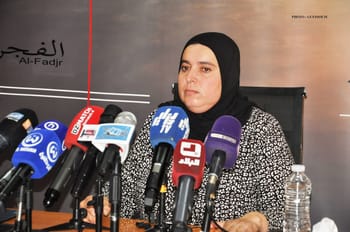 Femme en hijab lors d'une conférence de presse avec microphones.