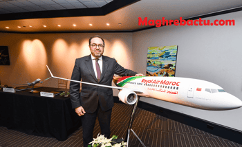 Homme en costume devant un modèle réduit d'avion Royal Air Maroc.