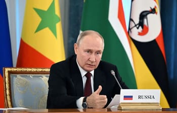 Vladimir Poutine à une réunion avec drapeaux africains en arrière-plan.