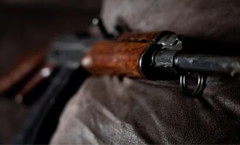 Fusil de chasse avec crosse en bois sur un fond sombre.