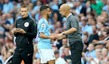 Guardiola et Mahrez se saluent sur le terrain de football.