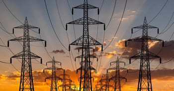 Lignes électriques haute tension contre un ciel de coucher de soleil.
